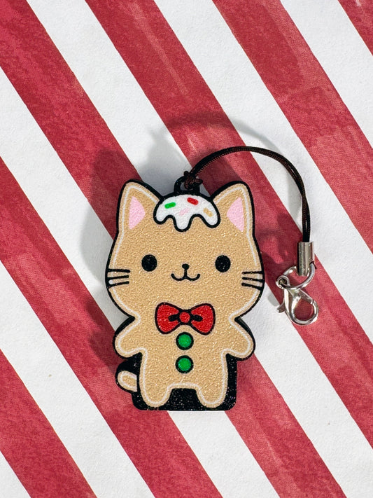 Gingerbread cat Tab Buddy keychain on a red and white striped background
