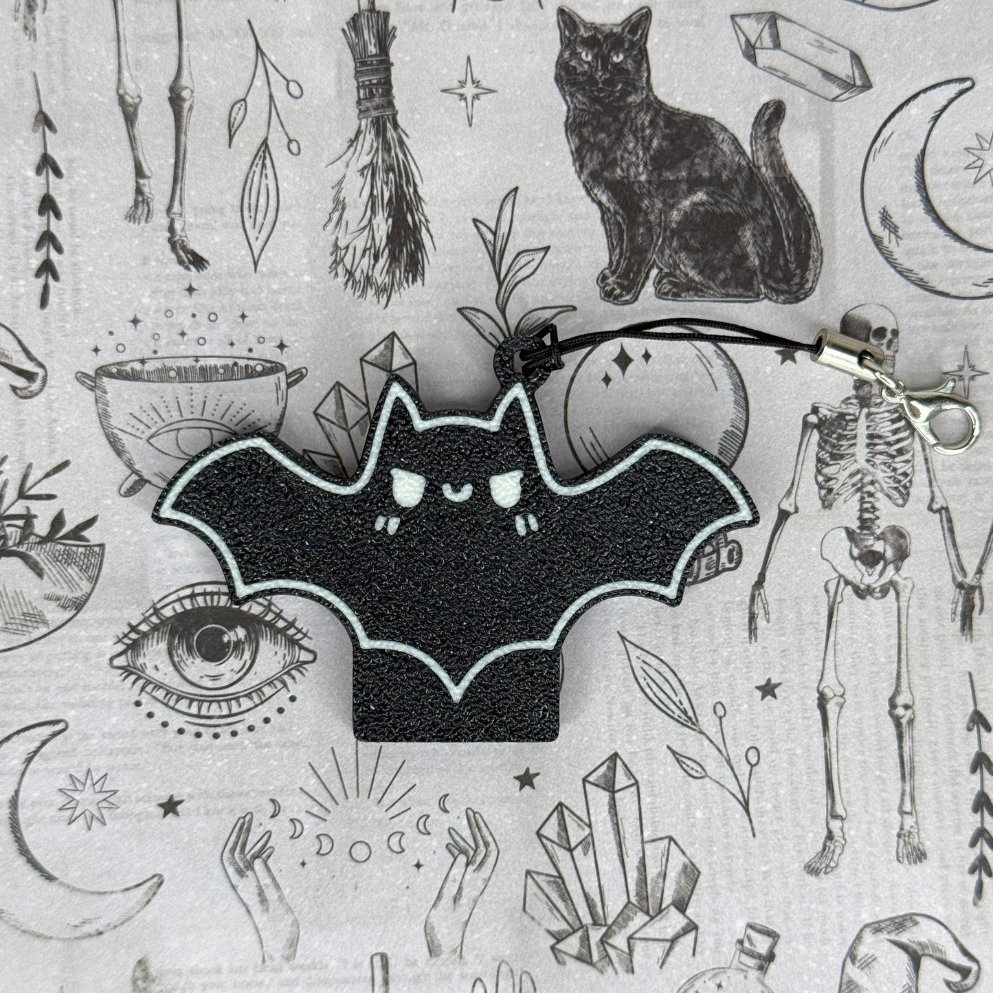 Black bat design Tab Buddy on a gray background with various symbols and objects.