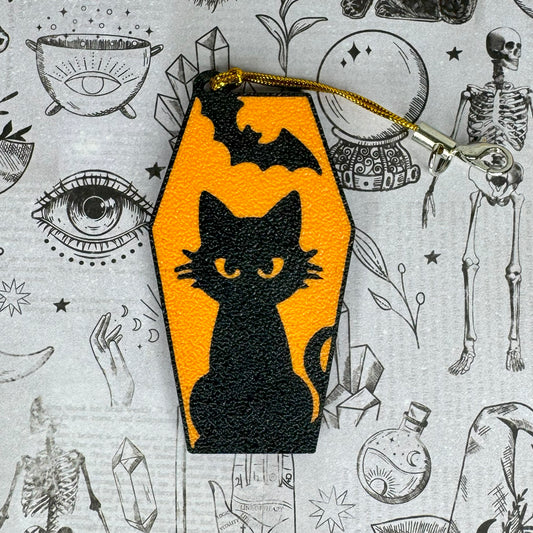 Black cat in a coffin Tab Buddy on an orange background with a Halloween-themed pattern in the background.