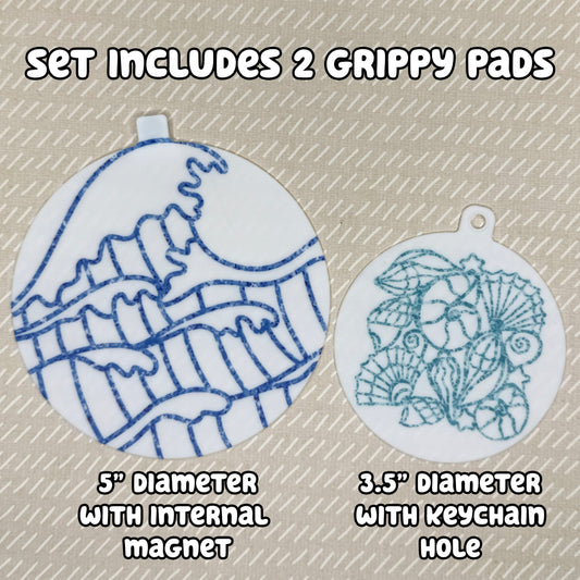 Two circular ocean and shells-themed Grippy Pads are shown atop a beige background. Text reads, "Set includes 2 Grippy Pads. 5" Diameter with internal magnet. 3.5" diameter with keychain hole."