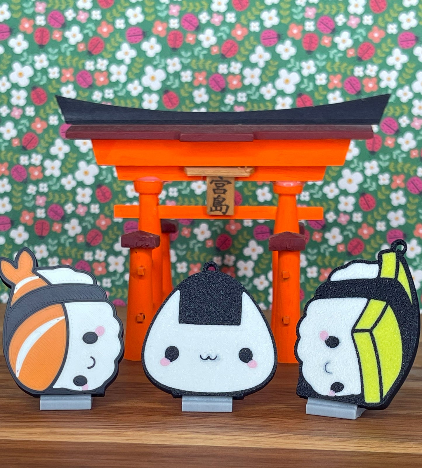Three sushi themed Tab Buddies with a traditional Japanese torii gate and floral background
