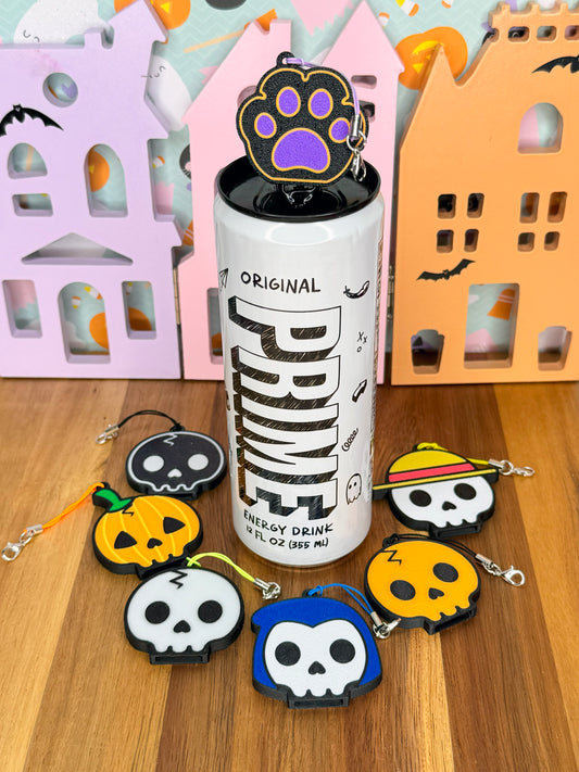 Can with halloween themed caw paw Tab Buddy on top, surrounded by colorful Tab Buddies on a wooden surface.