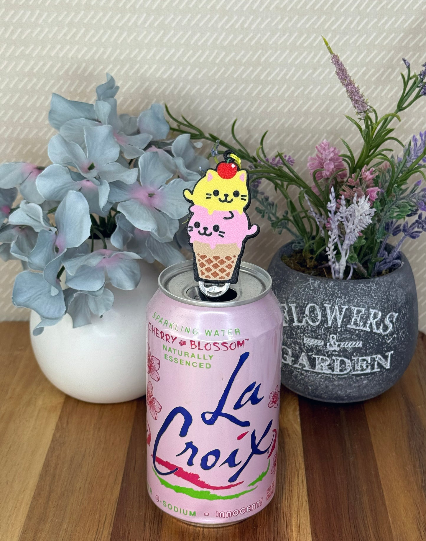 La Croix sparkling water can with a cute kitty-themed ice cream cone Tab Buddy on top, surrounded by greenery and flowers.