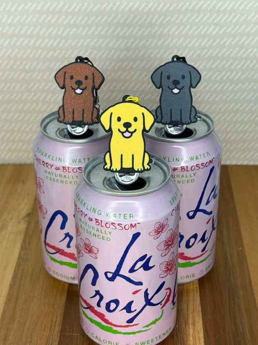 Labrador-inspired Soda Tab Buddies in yellow, chocolate and black rest atop the tabs of pink soda cans.