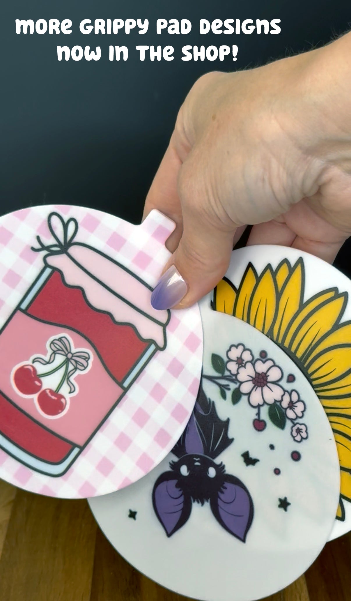 Hand holding three circular Grippy Pads with varying designs, with text indicating 'more grippy pad designs now in the shop.'