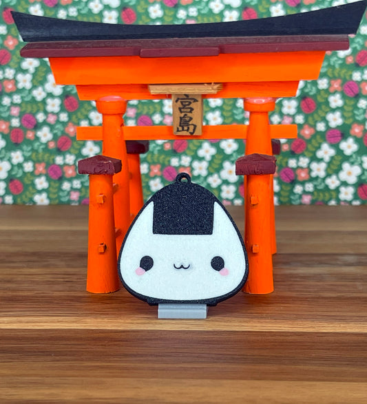 Onigiri-shaped Tab Buddy with a stand in front of an orange torii gate with a floral background
