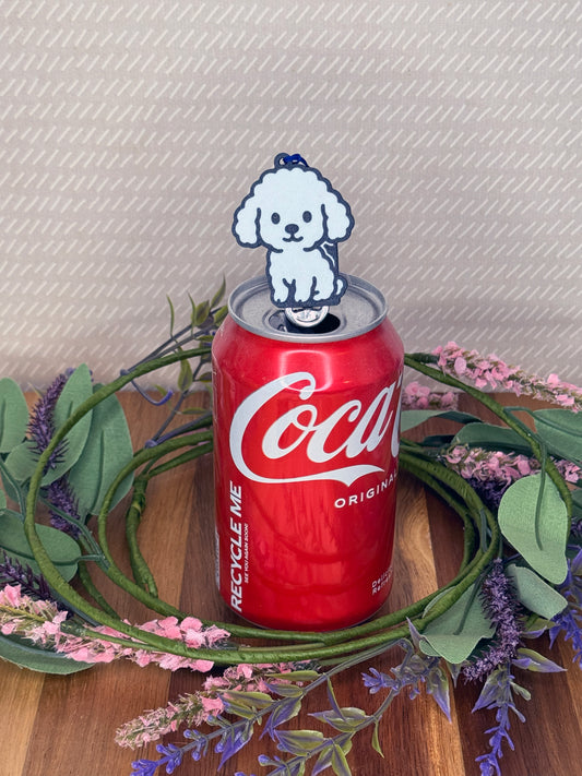A White Poodle-inspired Tab Buddy rests atop an open can tab with a beige background and floral accents.