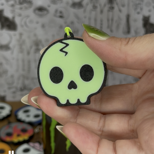 Hand holding a small green skull-shaped Tab Buddy with a blurred background