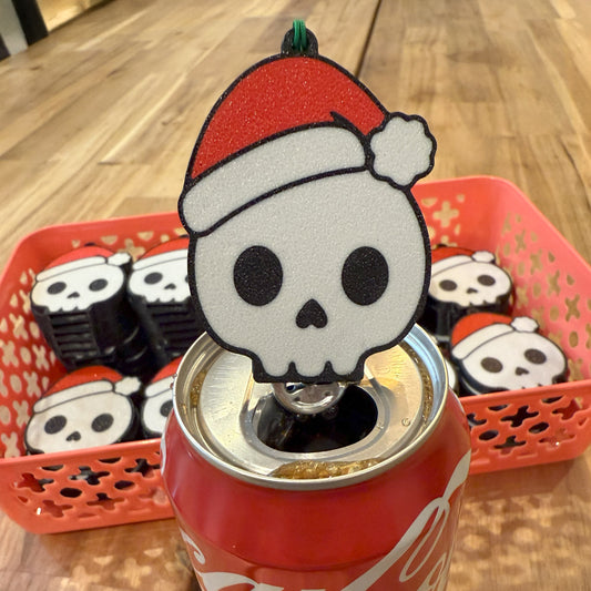 Santa skull-shaped Tab Buddy with on a Coca-Cola can, with more skull-shaped Tab Buddies in the background.
