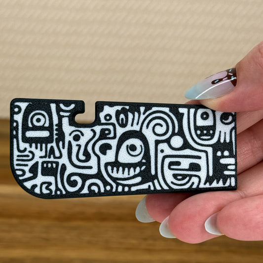 Hand holding a black and white doodle pattern Tab Buddy XL against a beige background