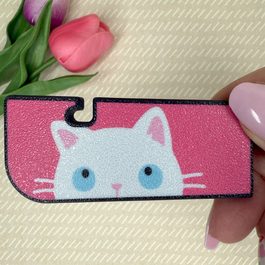 Tab Buddy XL with a cat design held by a hand, with pink tulips in the background.