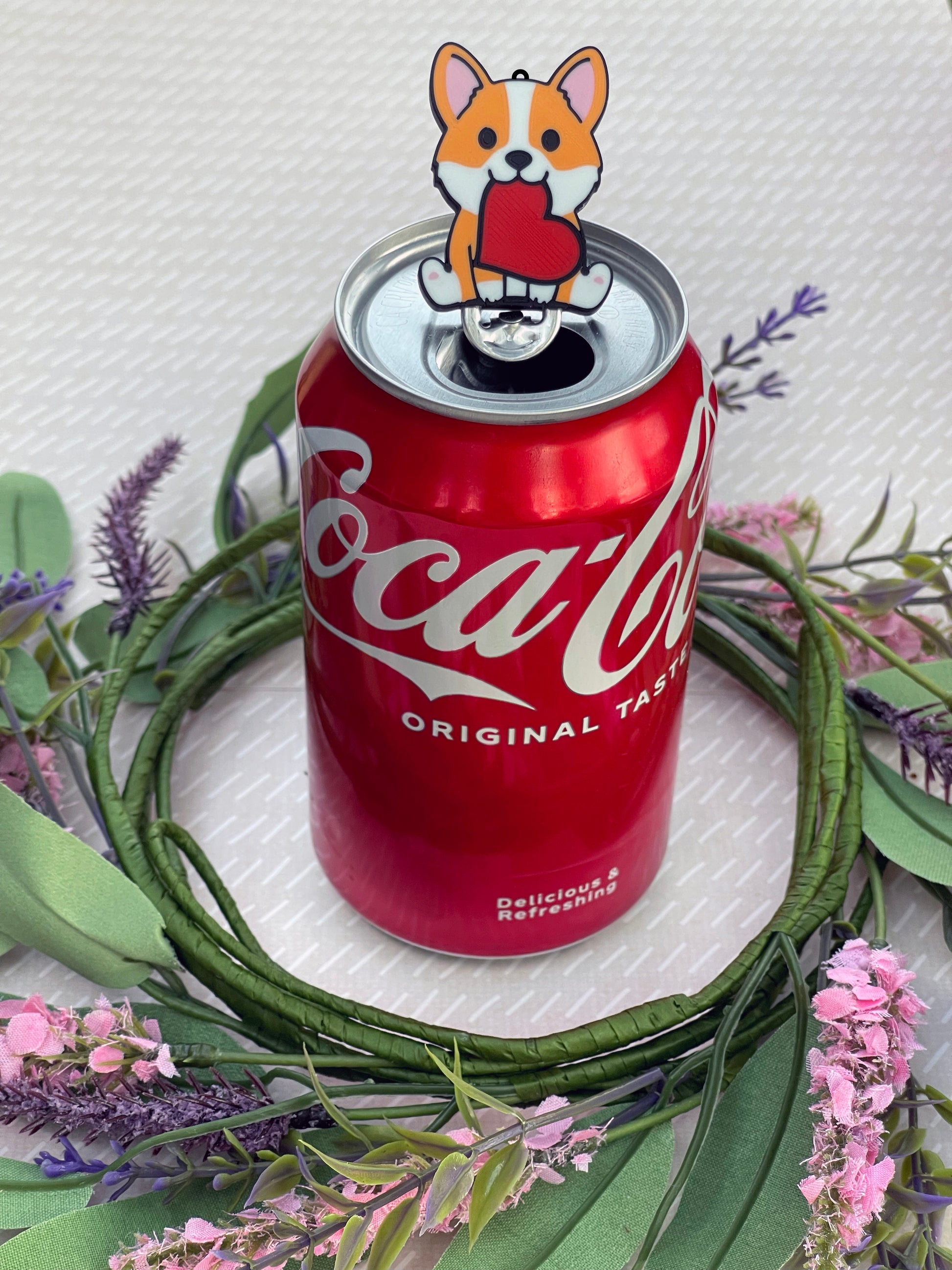 Soda can with a dog-shaped Tab Buddy on a decorative wreath with flowers.