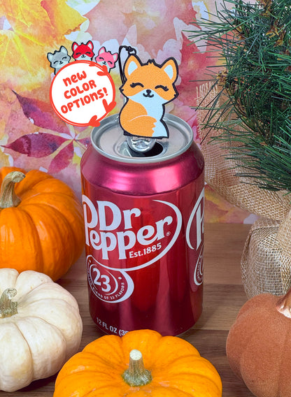 Dr Pepper can with an orange fdx-shaped Tab Buddy on top, surrounded by pumpkins and autumn leaves. Text reads "new color options" with other color fox Tab Buddies shown.