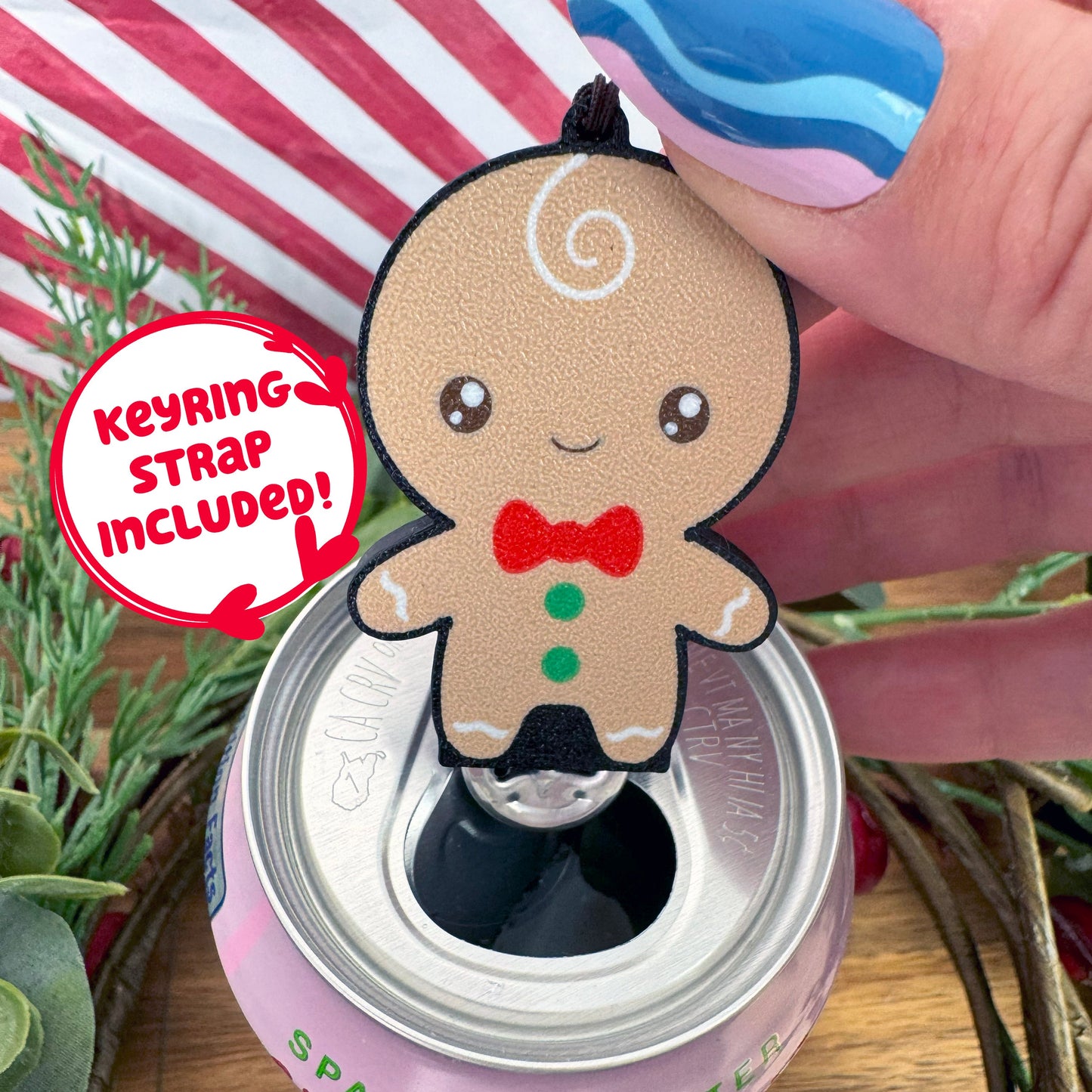 Gingerbread man Tab Buddy with keyring strap attached rests atop a soda can with festive background