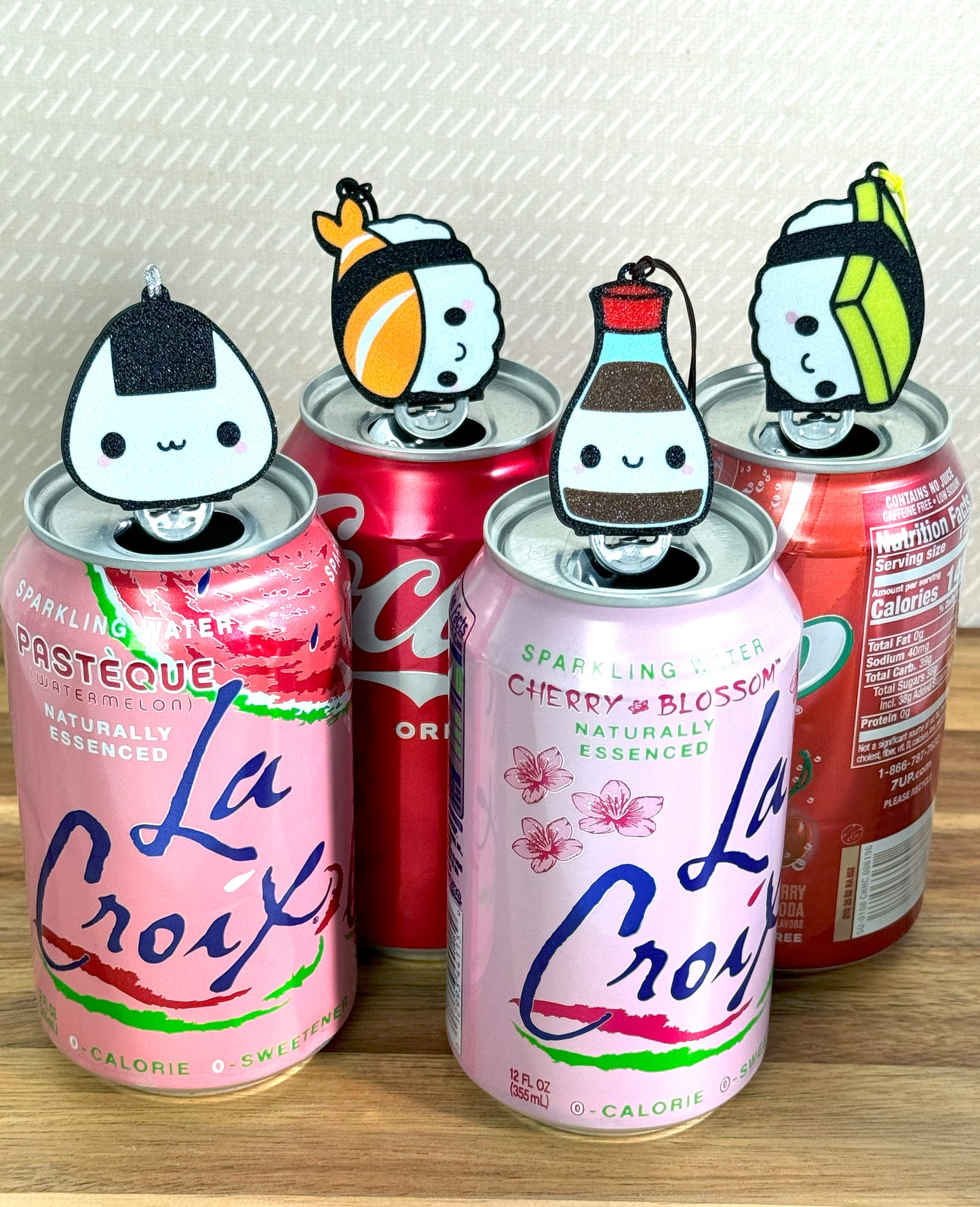 Four cans with sushi themed character Tab Buddies on a wooden surface.