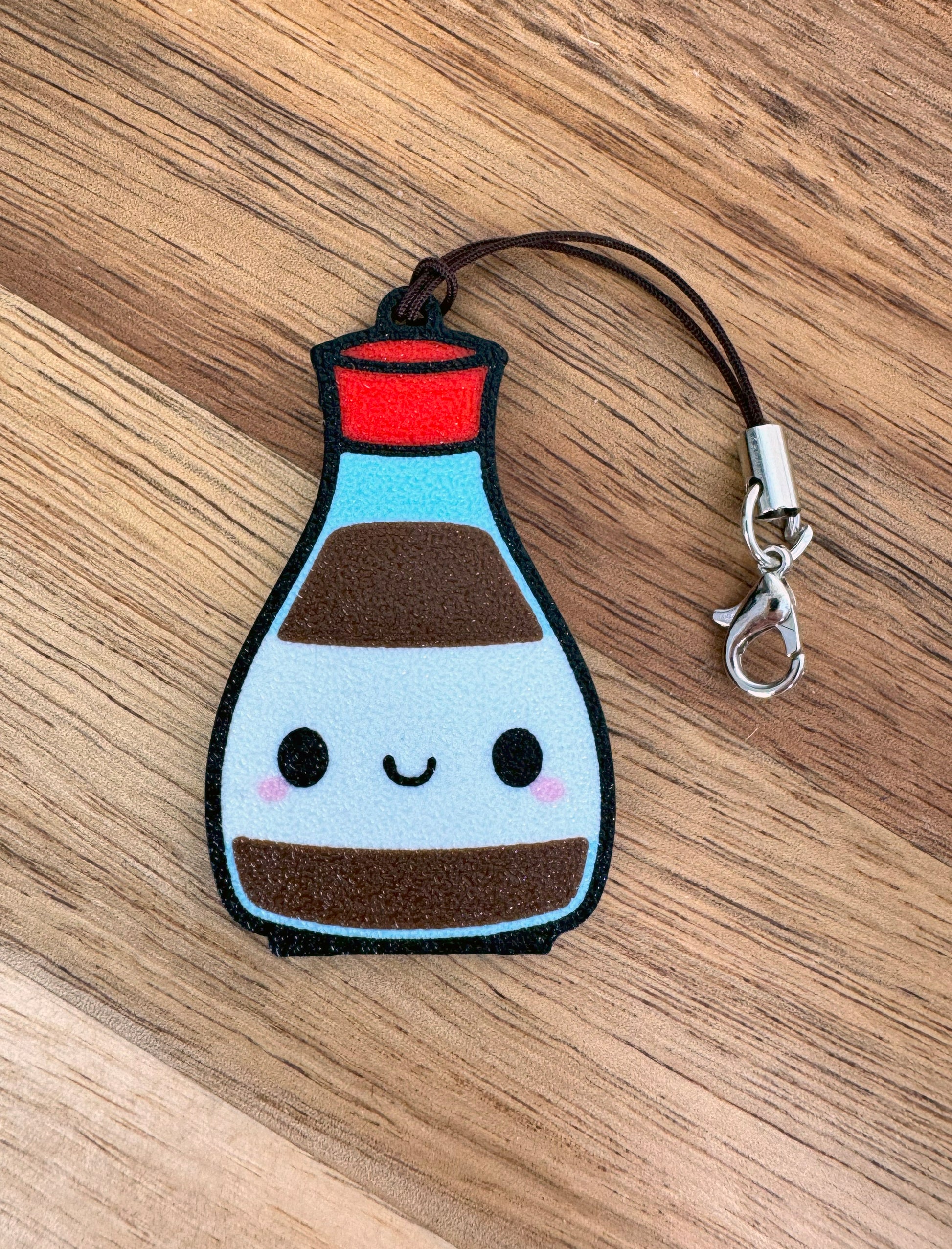 Kawaii-style Soy Sauce bottle-shaped Tab Buddy keychain on a wooden surface