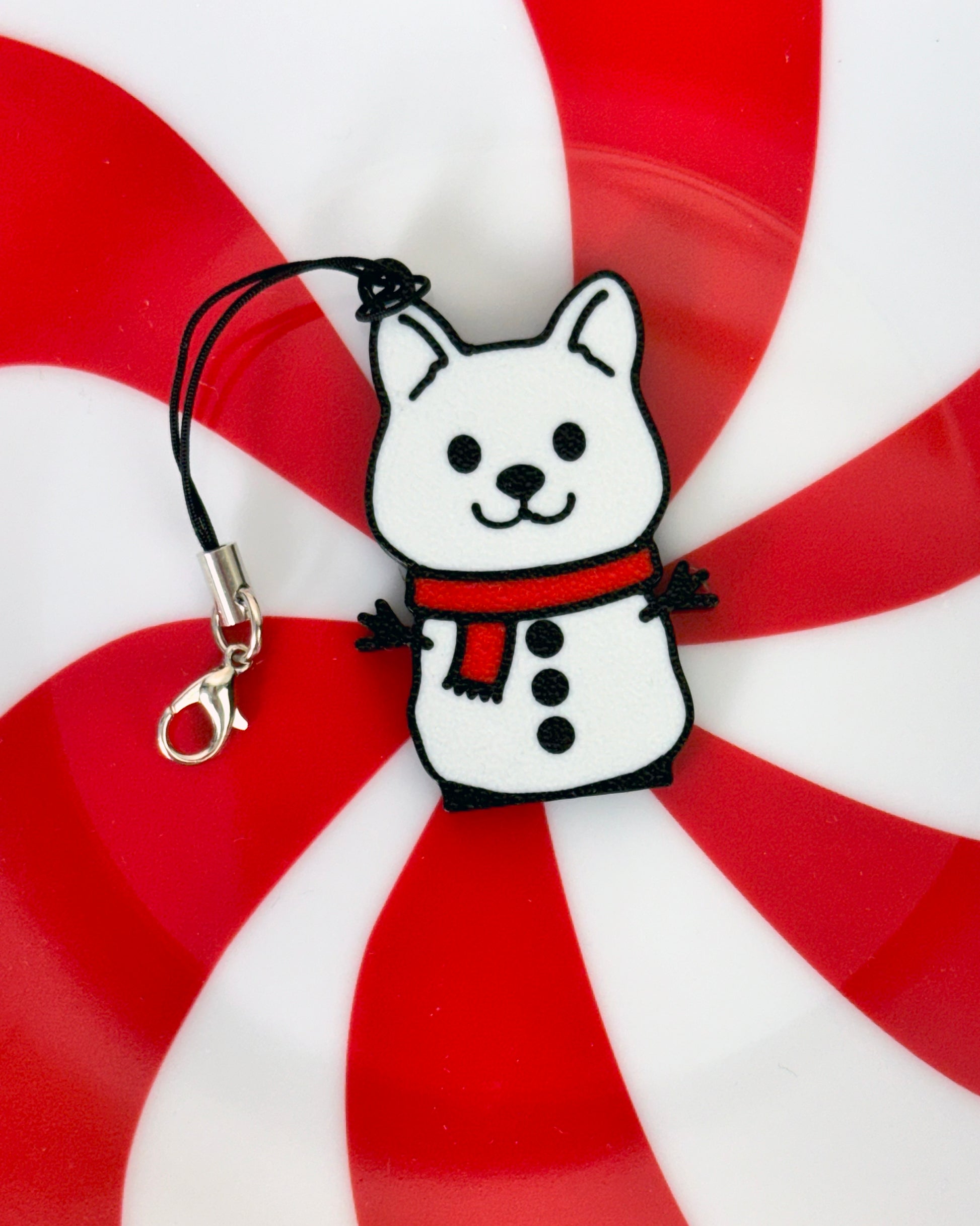Snowman dog-shaped Tab Buddy keychain with a red scarf on a peppermint candy background