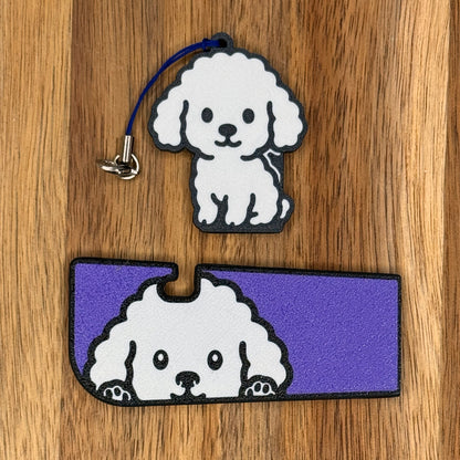 A matching set of whote Poodle-inspired soda Tab Buddy and Tab Buddy XL rest atop a wooden surface.