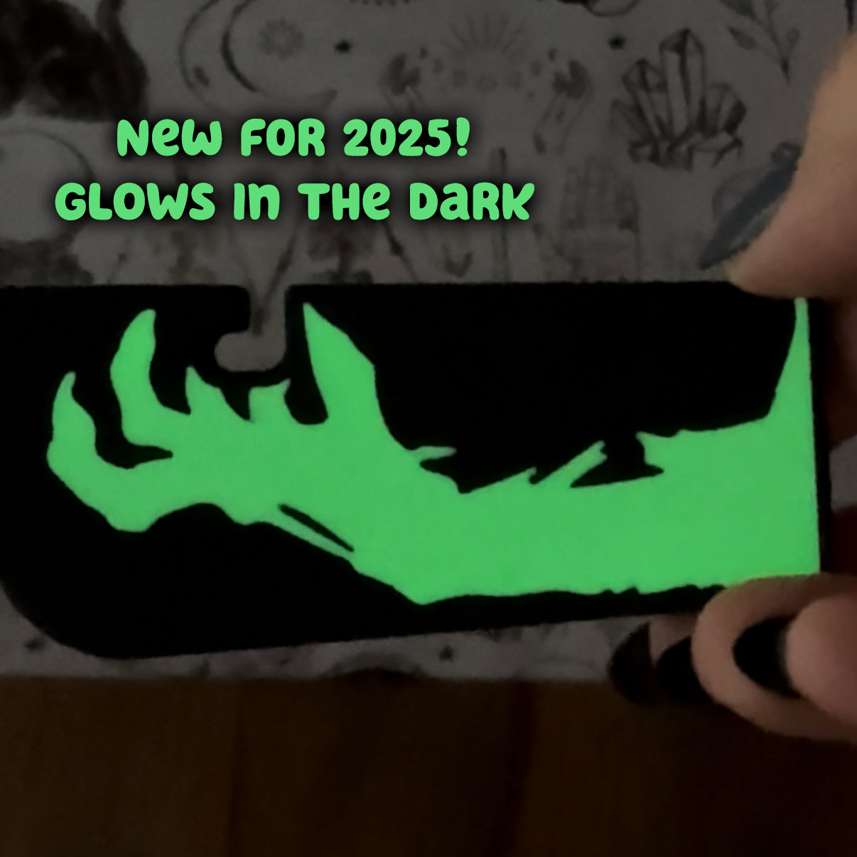 Glowing green zombie hand on a black Tab Buddy XL with text 'New for 2025! Glows in the dark' on a patterned background.