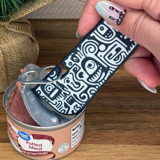 Hand using a doodle patterned Tab Buddy XL on a can with a decorative background.