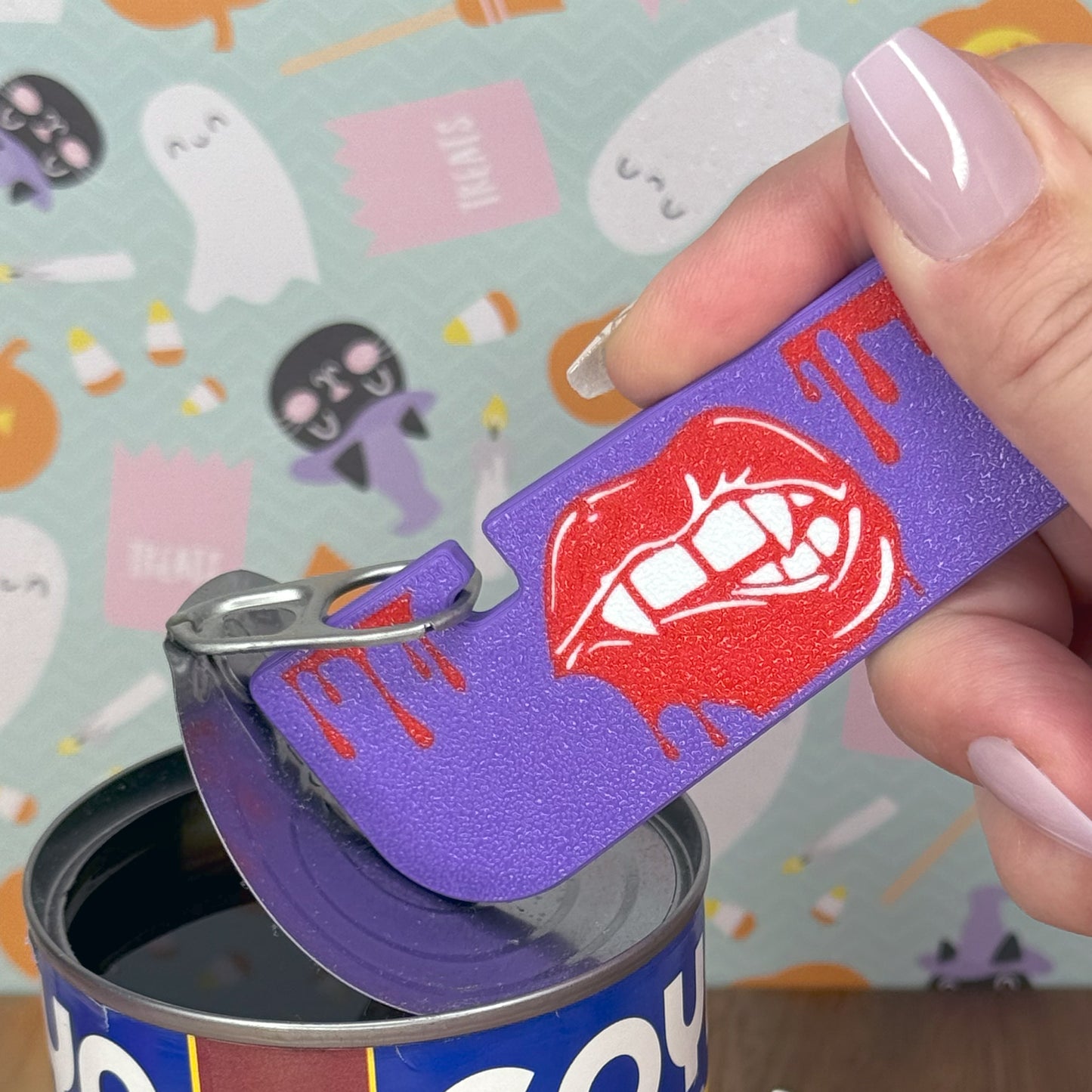 Purple Tab Buddy XL with red graphic on a can against a colorful Halloween-themed background