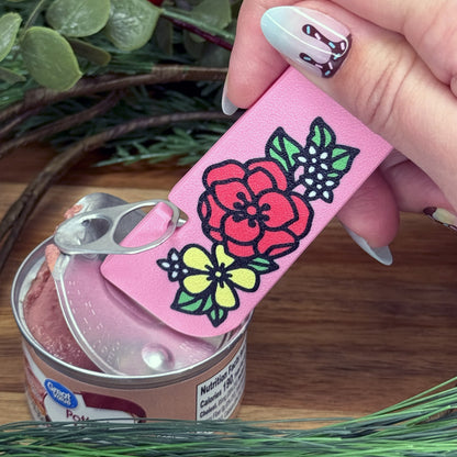 Pink Tab Buddy XL with floral design opening a can on a wooden surface.