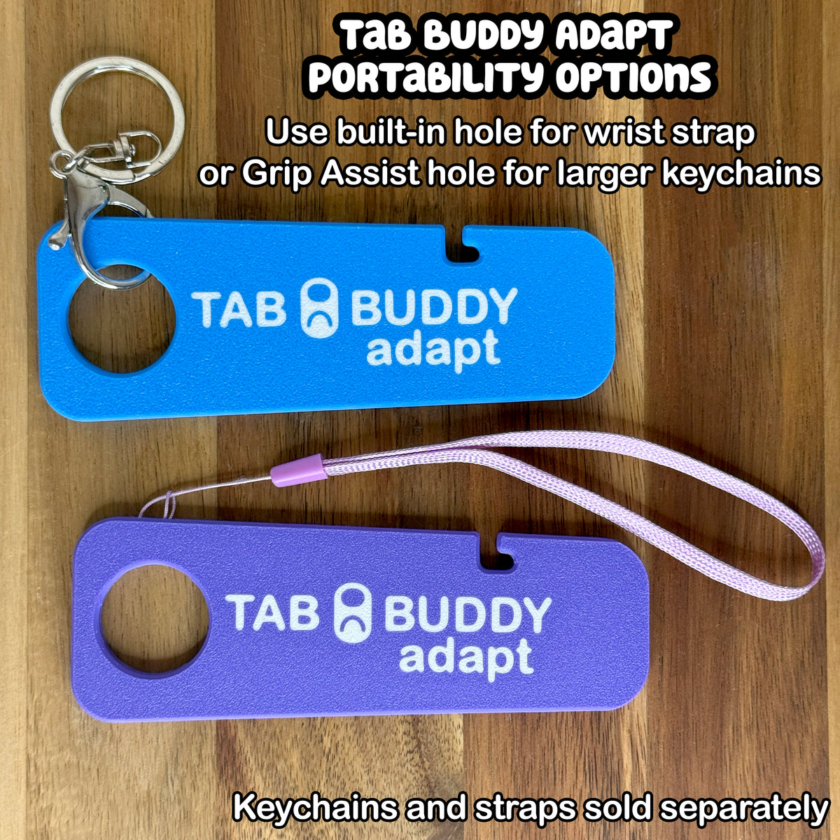 Two Tab Buddy Adapts in sky blue and purple are shown against a wooden background with different portability optioins. Text notes to use the built-in hole for wrist strap or the Grip Assist hole for larger keychains. Keychains and straps each sold separately.