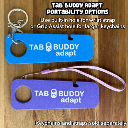 Two Tab Buddy Adapts in sky blue and purple are shown against a wooden background with different portability optioins. Text notes to use the built-in hole for wrist strap or the Grip Assist hole for larger keychains. Keychains and straps each sold separately.