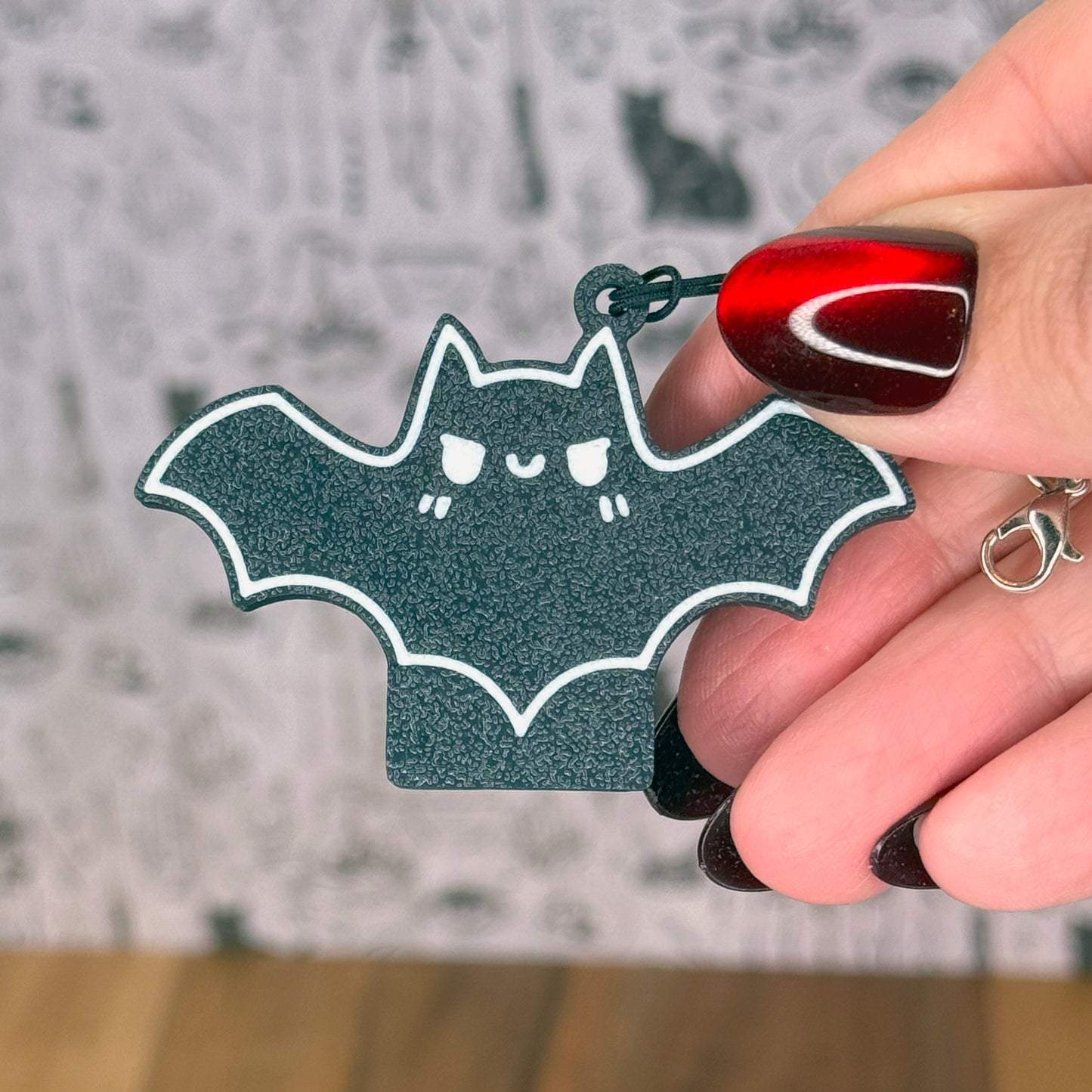 Hand holding a bat-shaped Tab Buddies with a blurred background