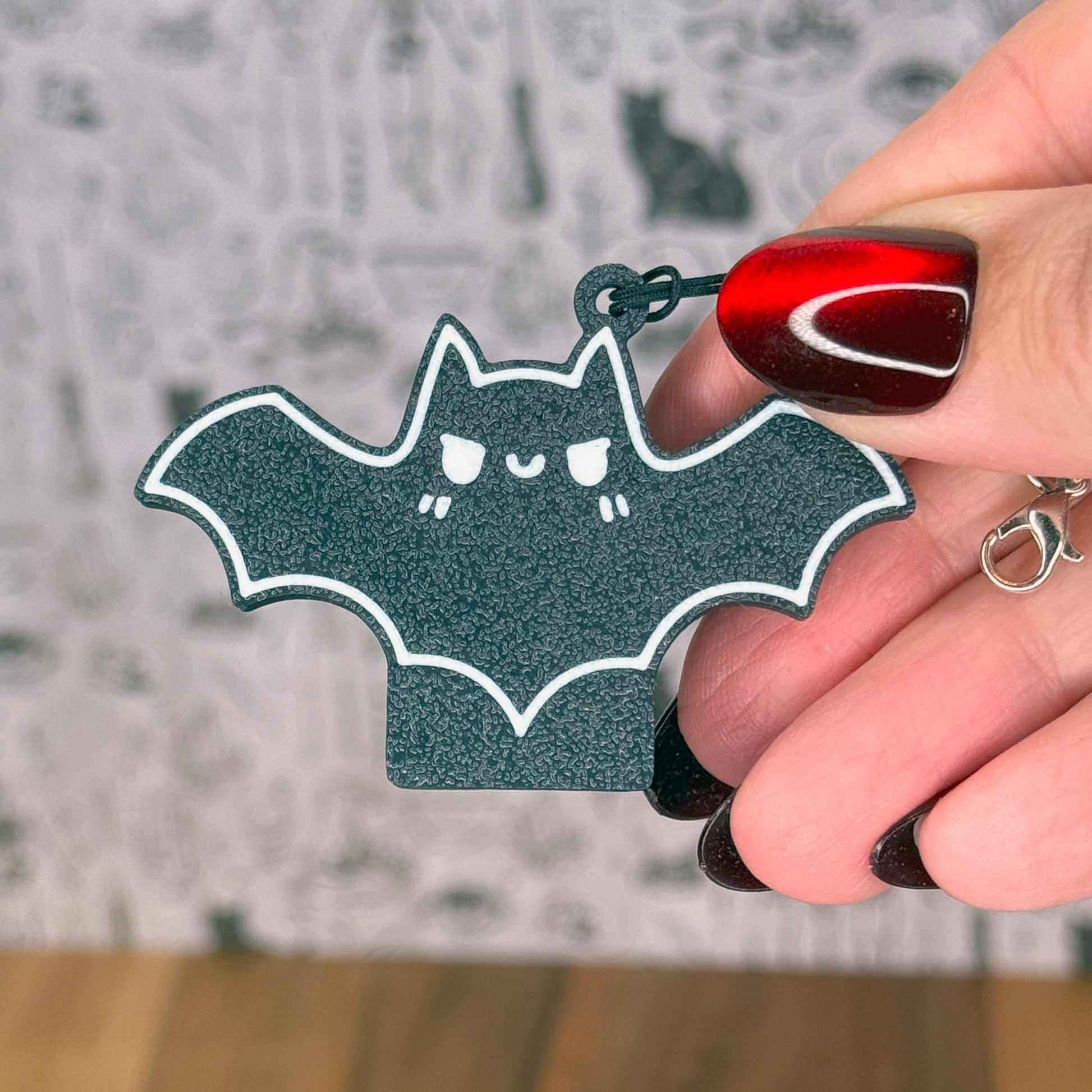 Hand holding a bat-shaped Tab Buddies with a blurred background