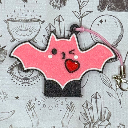 Pink bat-shaped Tab Buddy with a heart on a gray background with illustrations