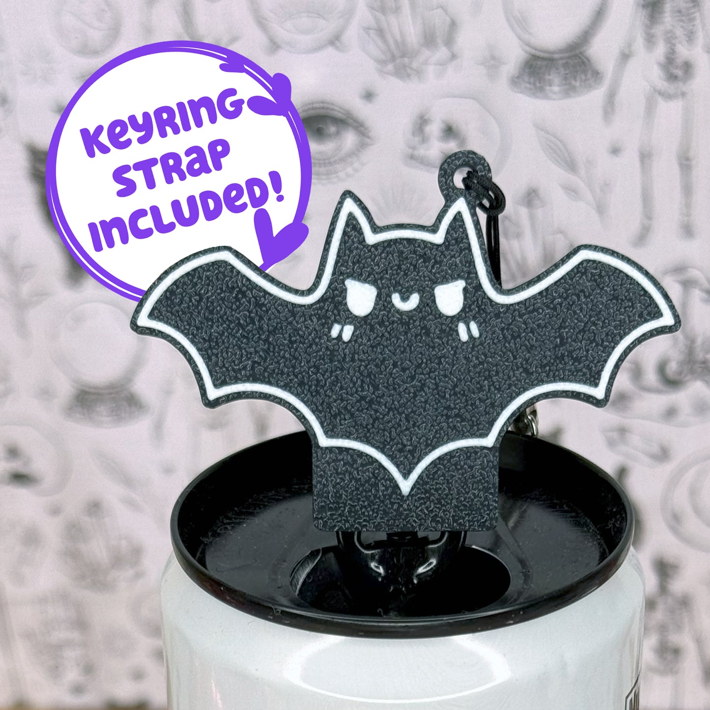 Black bat-shaped Tab Buddy on a white can with a purple text bubble indicating 'Keyring strap included!'.