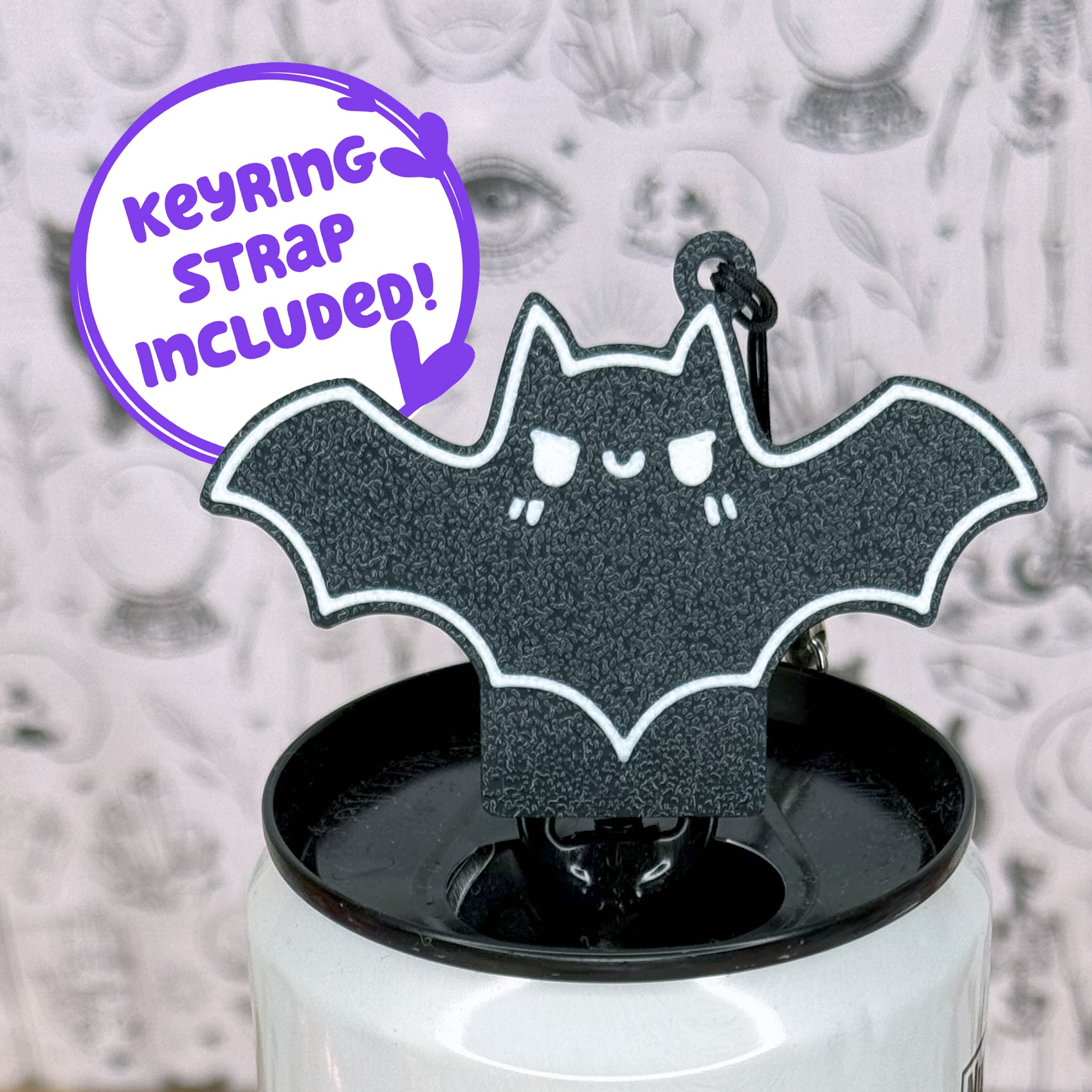 Black bat-shaped Tab Buddy on a white can with a purple text bubble indicating 'Keyring strap included!'.