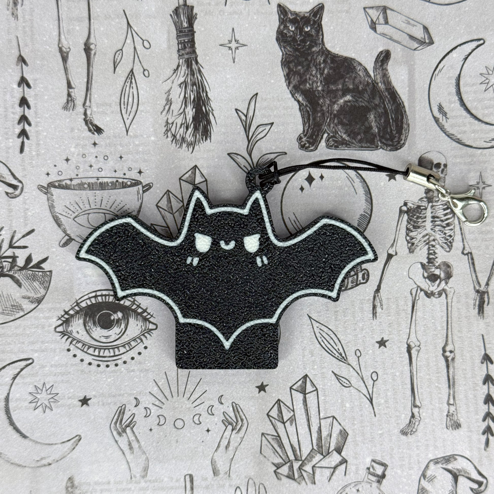 Black bat design Tab Buddy on a gray background with various symbols and objects.
