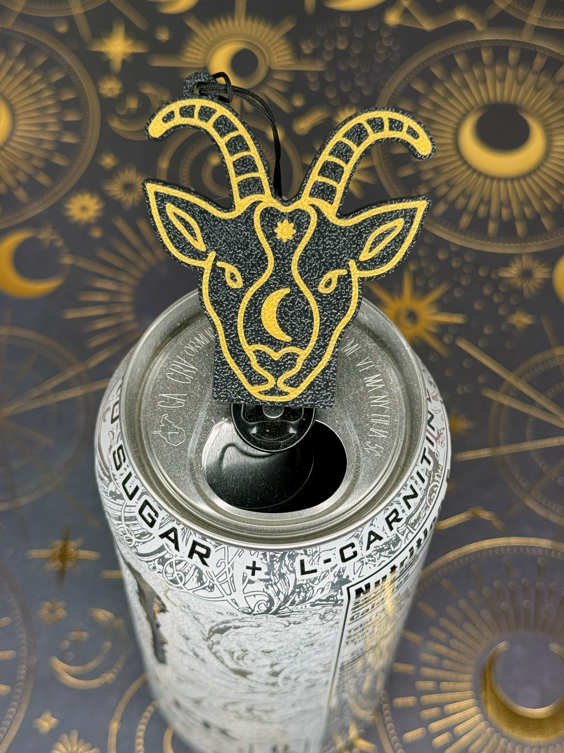 Can with a Capricorn goat head Tab Buddy on top against an astrological symbol background