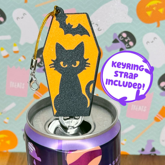 Halloween-themed Tab Buddy with a black cat design on an orange coffin, attached to a can against a colorful Halloween-themed background with text reading 'keyring strap included!'