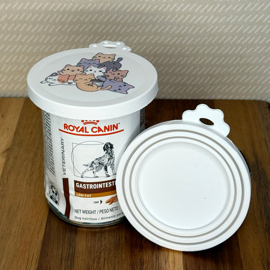 A can of pet food is sealed with a resusable silicone can cover. An additional lid is shown facing outward with multiple circular rings that stretch to seal various sized cans.