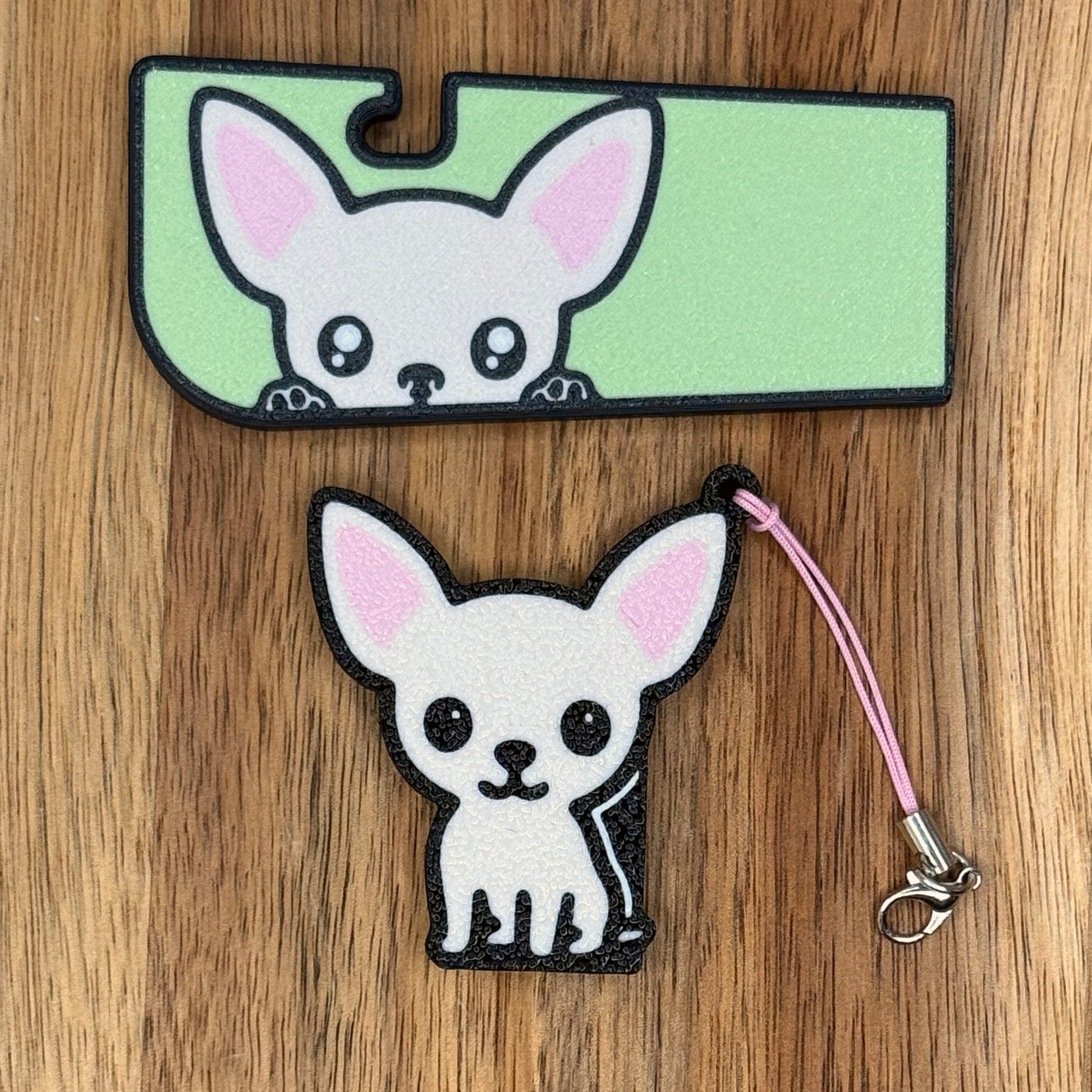 A matching set of Chihuahua-inspired soda Tab Buddy and Tab Buddy XL rest atop a wooden surface.