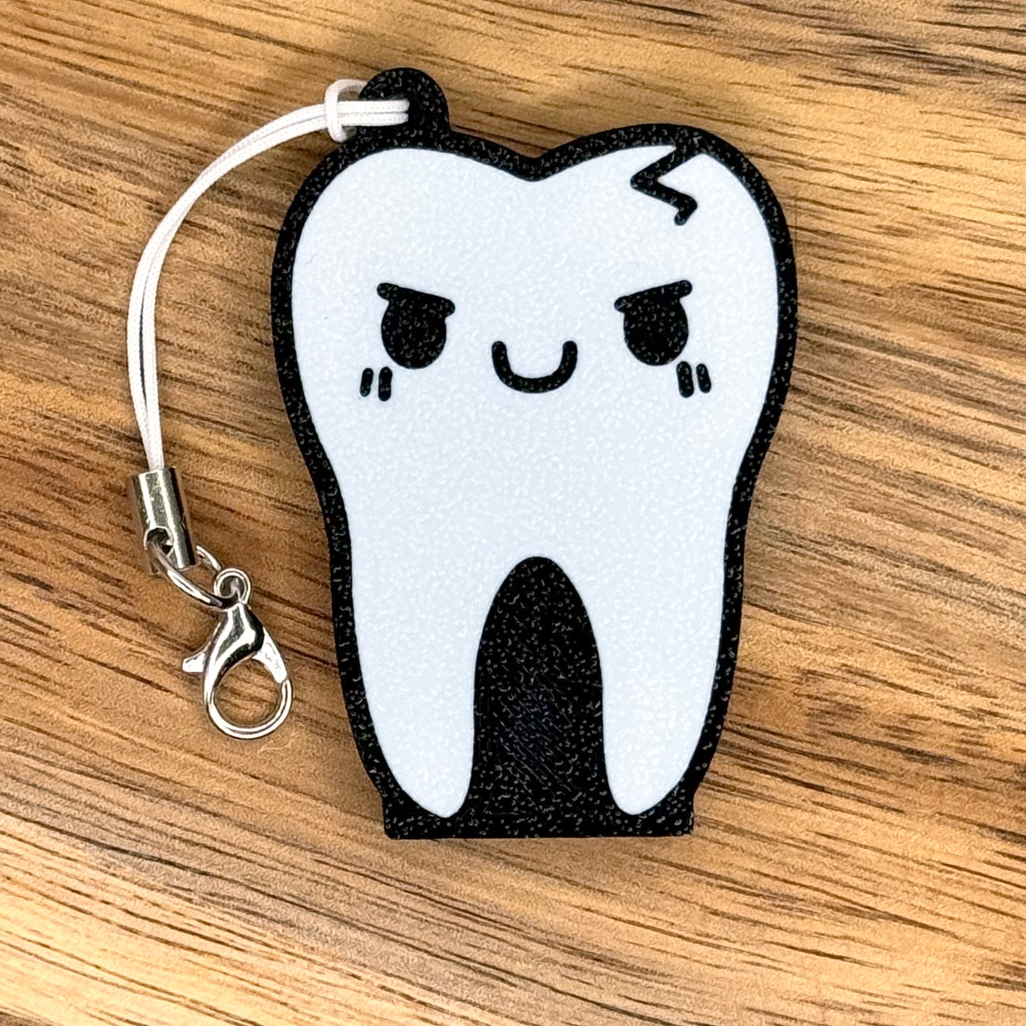 Tooth-shaped Tab Buddy with a happy face on a wooden surface