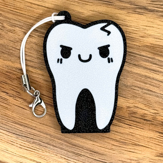 Tooth-shaped Tab Buddy with a happy face on a wooden surface