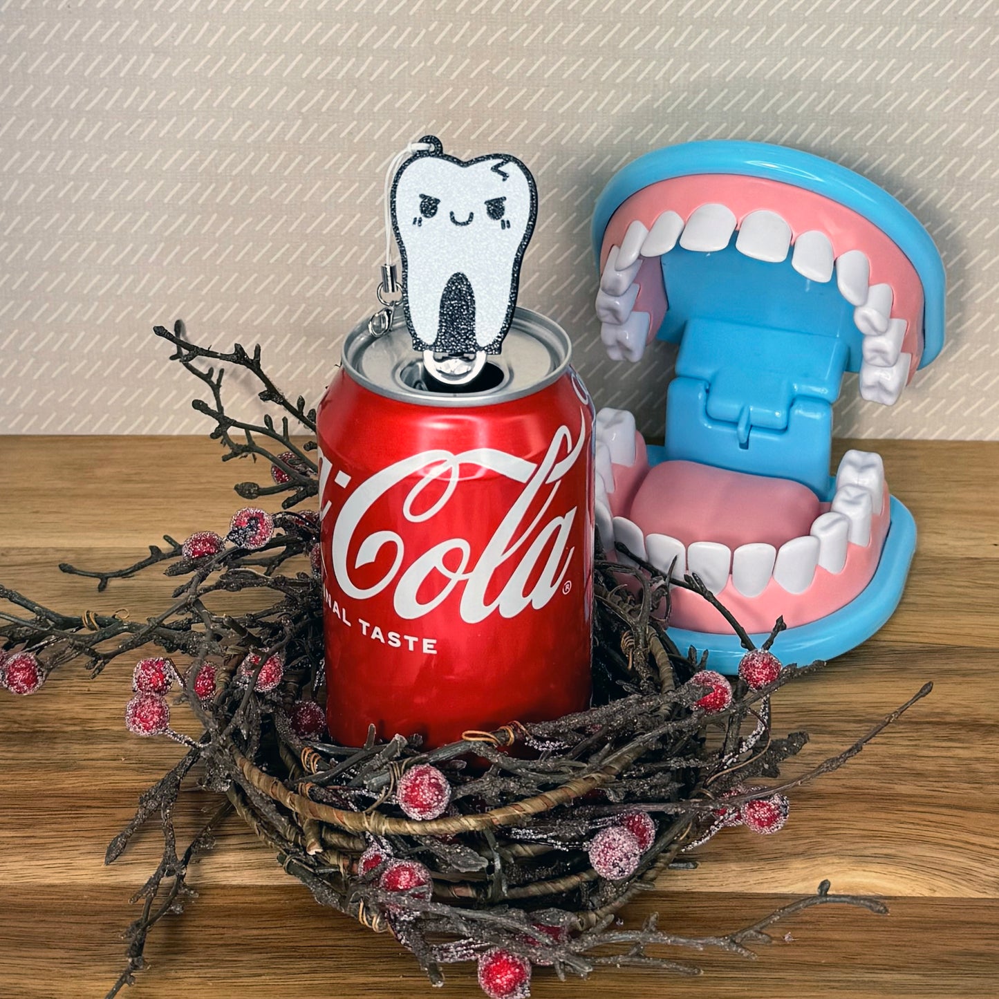 Soda can with a tooth-shaped Tab Buddy and dental model on a wooden surface.