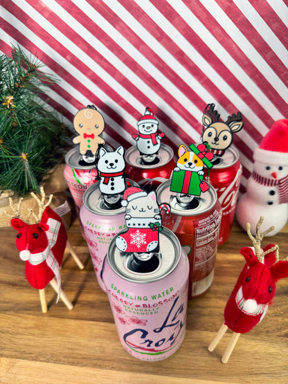 Festive Christmas Tab Buddies rest atop soda cans with a striped background