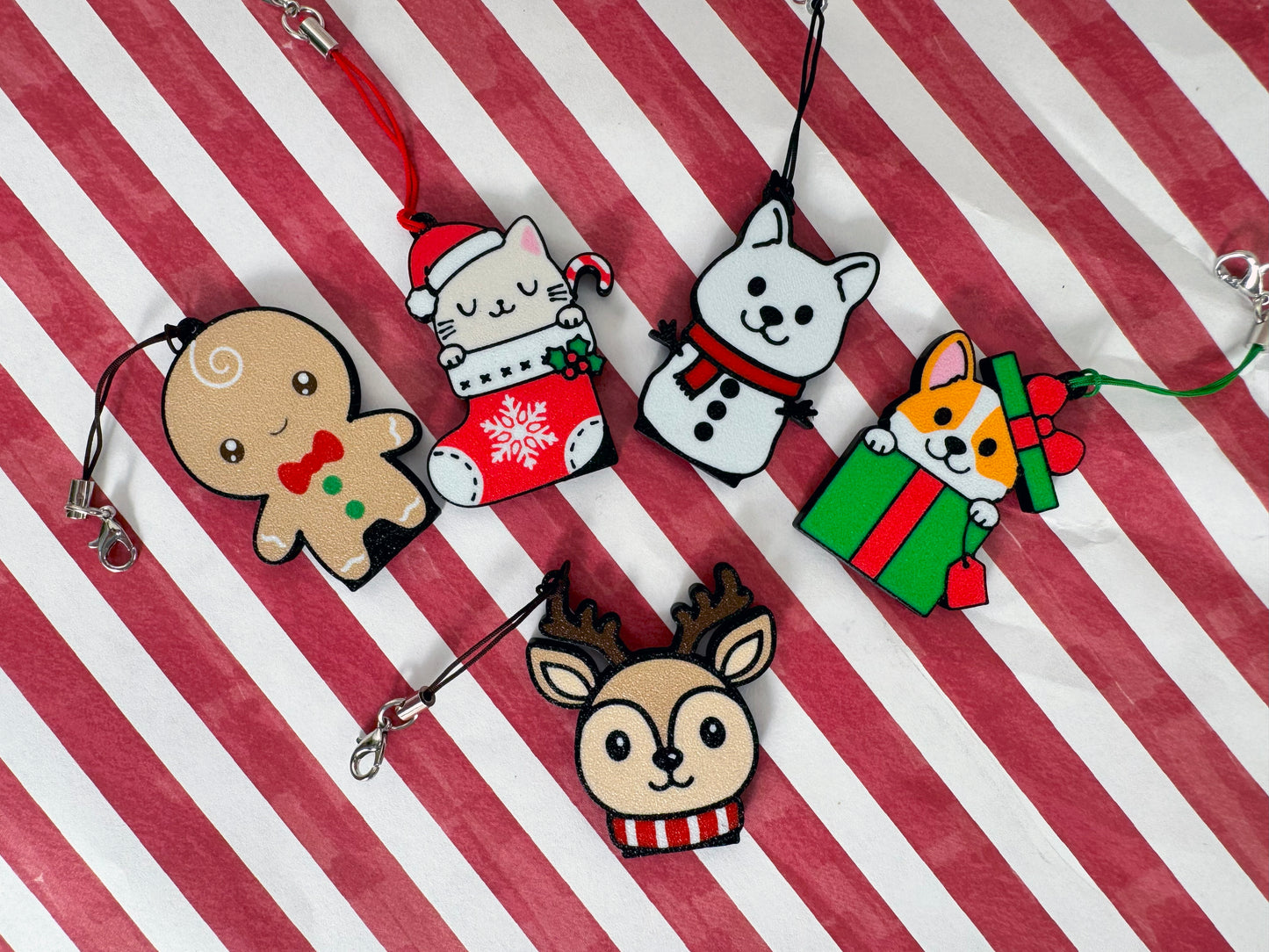 Set of Christmas-themed Tab Buddy keychains on a red and white striped background
