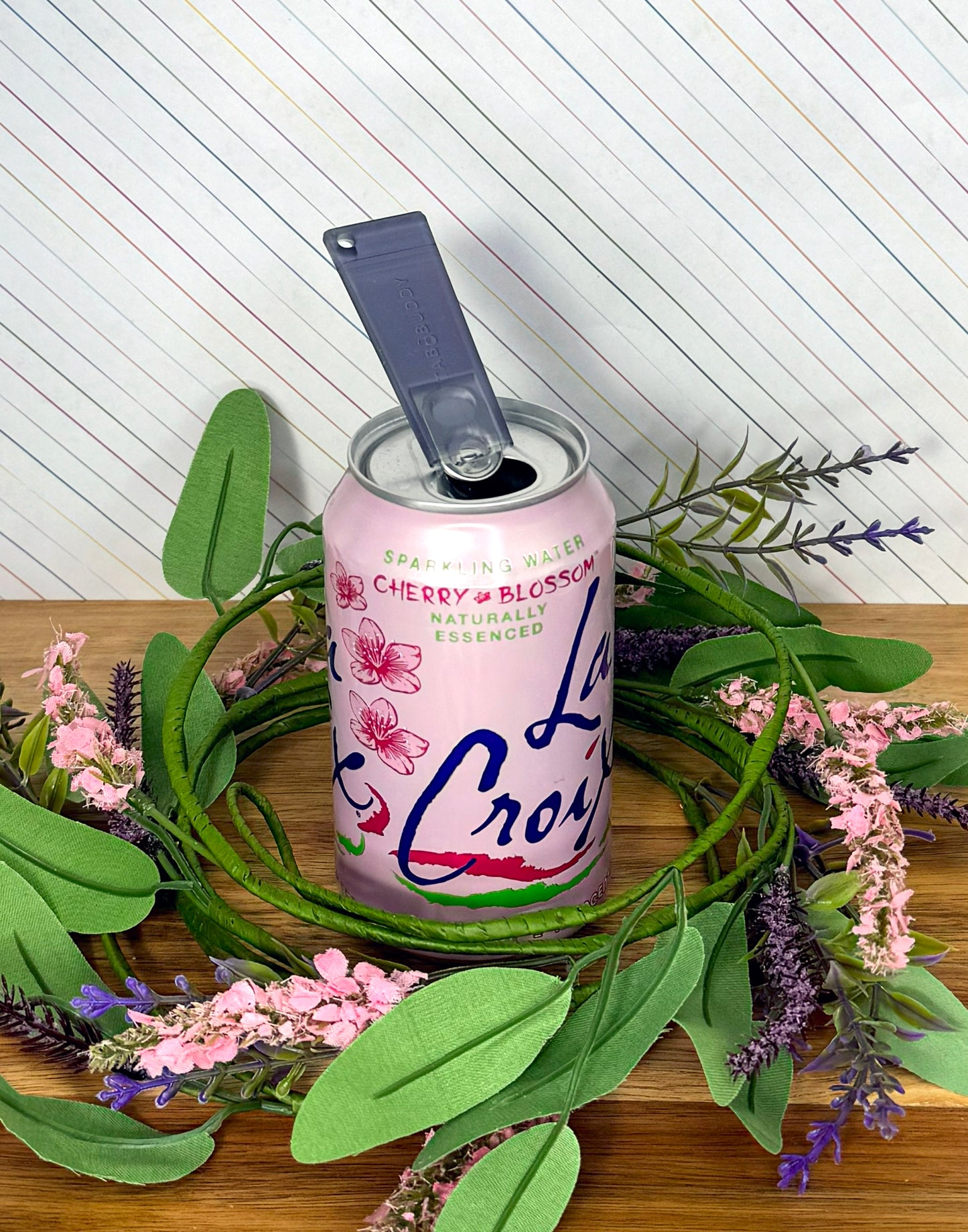 LaCroix cherry blossom sparkling water can with a translucent Onyx Tab Buddy Classic with background of decorative wreath, flowers and leaves.