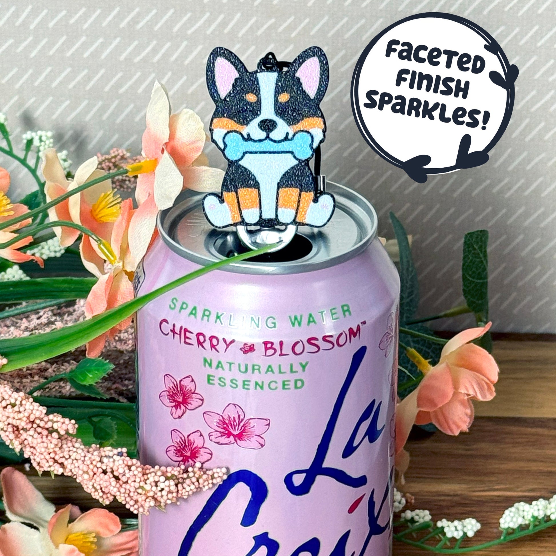 Water can with cherry blossom flavor, featuring a dog-shaped Tab Buddy and decorative elements with text that reads 'faceted finish sparkles!'