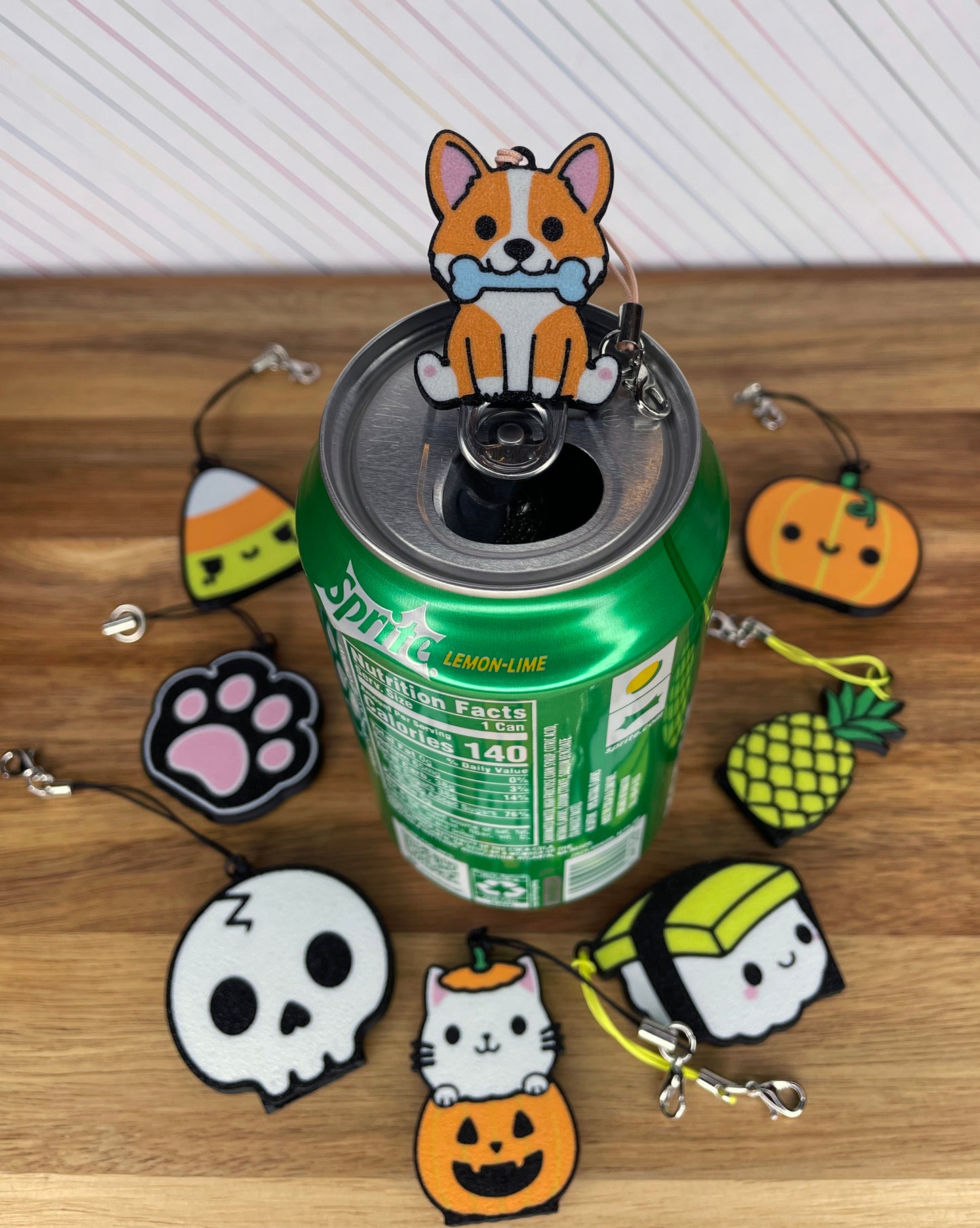 Collection of various Tab Buddies around a soda can on a wooden surface