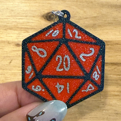 Red D20 dice Tab Buddy held by a hand on a wooden surface