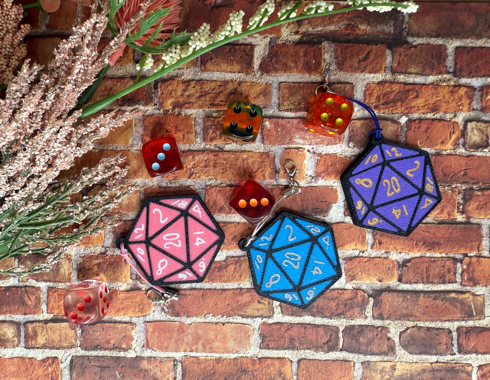 Pink, blue and purple D20 Tab Buddies on a brick background