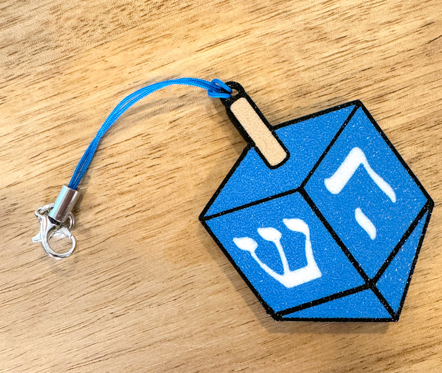 Blue dreidel Tab Buddy on a wooden surface