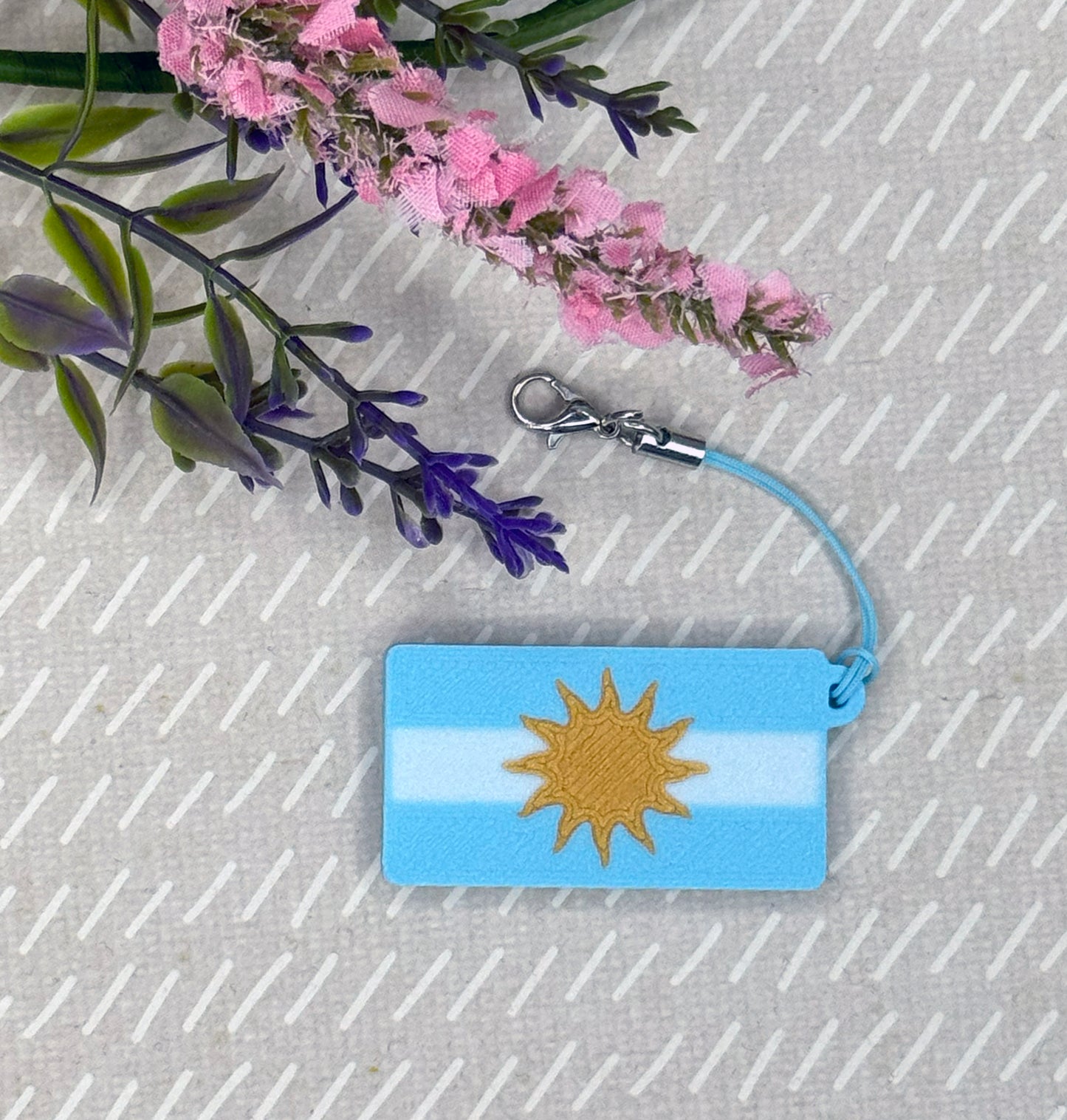 Tab Buddy with Argentinian flag design on a textured surface with flowers